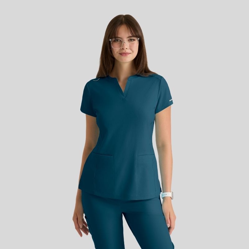Woman wearing teal medical scrub top and pants, short sleeves, v-neck, front pockets
